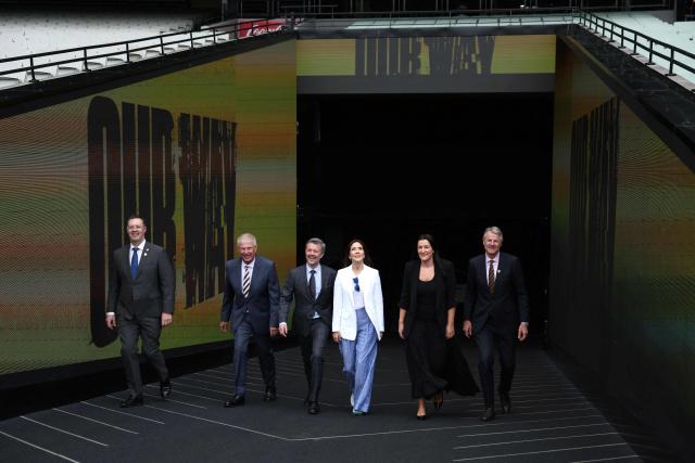 Denmark’s Queen Mary (C) reacts with King Frederik X (3rd L) as they walk with Laura Kane (2nd R), Executive General Manager of Football for AFL, and officials from Hawthorne Football Club during a visit to the Melbourne Cricket Ground (MCG) to meet with Hawthorn Football Club players and children from the Hawthorn Auskick League in Melbourne on March 17, 2026, as part of their five-day state visit to Australia. (Photo by MARTIN KEEP / POOL / AFP)
