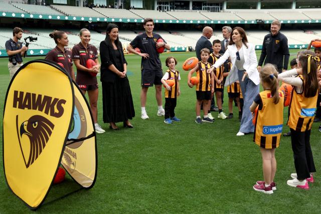 Denmark’s Queen Mary passes a ball towards a target during a visit to the Melbourne Cricket Ground (MCG) to meet with Hawthorn Football Club players and children from the Hawthorn Auskick League in Melbourne on March 17, 2026, as part of their five-day state visit to Australia. (Photo by MARTIN KEEP / POOL / AFP)
