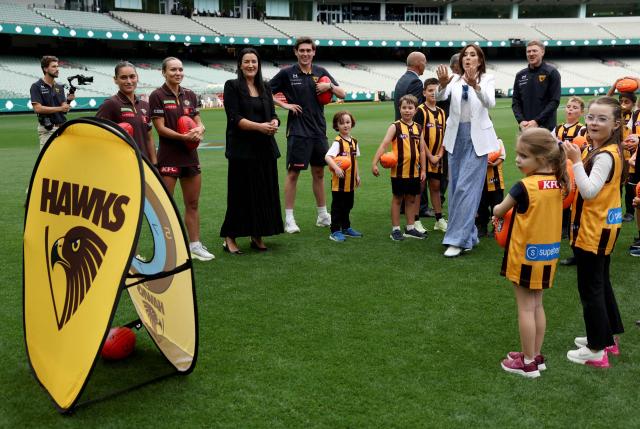 Denmark’s Queen Mary (C) reacts after passing a ball towards a target during a visit to the Melbourne Cricket Ground (MCG) to meet with Hawthorn Football Club players and children from the Hawthorn Auskick League in Melbourne on March 17, 2026, as part of their five-day state visit to Australia. (Photo by MARTIN KEEP / POOL / AFP)