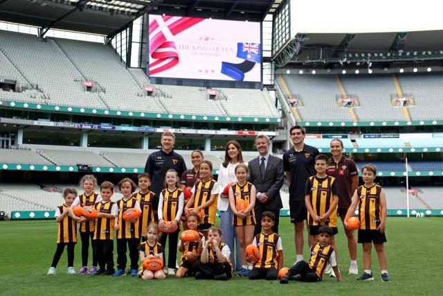 Denmark’s Queen Mary (C) and King Frederik X (5th R) pose for a photograph with players and officials from Hawthorne Football Club during a visit to the Melbourne Cricket Ground (MCG) to meet with Hawthorn Football Club players and children from the Hawthorn Auskick League in Melbourne on March 17, 2026, as part of their five-day state visit to Australia. (Photo by MARTIN KEEP / POOL / AFP)