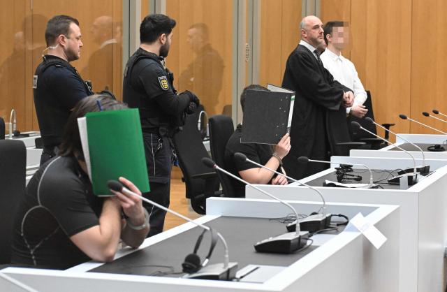 Three Ukrainian defendants, who are accused for plotting to send exploding parcels from Germany to Ukraine on the orders of a Russian intelligence service, wait for the start of their trial in the courtroom of the higher regional court in Stuttgart-Stammheim, southern Germany on March 17, 2026. Three Ukrainians go on trial in Germany, for allegedly  plotting sabotage attacks in Germany and Ukraine as part of what Berlin calls a campaign of Russian "hybrid" operations.
The suspects are accused of trying to send parcels that would "ignite in Germany or elsewhere on their way to parts of Ukraine not occupied by Russia". (Photo by THOMAS KIENZLE / AFP) / / EDITORS NOTE:  According to court's ruling the face of the defendants should be made unrecognizable