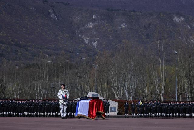 TOPSHOT - A French soldier of "Troupes de montagne" of Chasseurs Alpins (Alpine Hunters) holds a portrait in front of the coffin of Chief Warrant Officer Arnaud Frion who was killed in a drone attack in Erbil on March 12, 2026, during a national tribute ceremony at the 7th Alpine Chasseurs Battalion in Varces, southeastern France on March 17, 2026. Arnaud Frion was killed and six other French soldiers were wounded on March 12, 2026 evening in a drone attack in the Erbil region of Iraqi Kurdistan, French authorities announced, lamenting the first death within the French army in the context of the war in the Middle East. (Photo by Alex MARTIN / AFP)