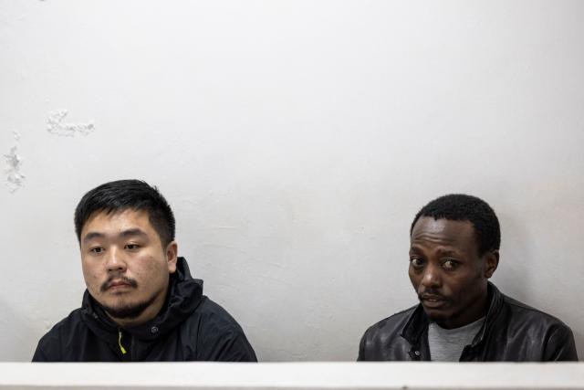 Chinese national, Zhan Kequn (L) sits at the Jomo Kenyatta International Airport (JKIA) law courts with co-accused Kenyan national Charles Mwangi (R), before taking a plea against charges of dealing in wildlife species contrary to laws regulating wildlife conservation preffered after both we're found in possession of more than two thousand live ants intended to be trafficked internationally in Nairobi on March 17, 2026. (Photo by Tony KARUMBA / AFP)