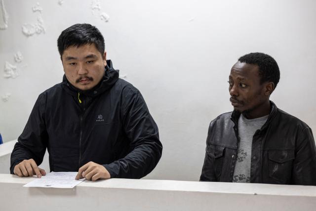 Chinese national, Zhan Kequn (L) sits at the Jomo Kenyatta International Airport (JKIA) law courts with co-accused Kenyan national Charles Mwangi (R), before taking a plea against charges of dealing in wildlife species contrary to laws regulating wildlife conservation preffered after both we're found in possession of more than two thousand live ants intended to be trafficked internationally in Nairobi on March 17, 2026. (Photo by Tony KARUMBA / AFP)
