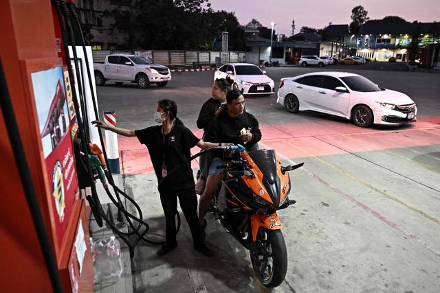 An employee refuels a motorcycle at a Caltex petrol station in the northern Thai province of Chiang Rai on March 17, 2026, following import disruptions caused by the Middle East war. Oil prices rose again on March 17 as Iran launched fresh attacks on crude-producing neighbours, while stock markets were higher ahead of key central bank meetings. (Photo by Lillian SUWANRUMPHA / AFP)