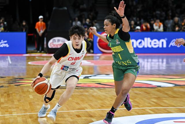 China's Yang Shuyu (L) dribbles the ball while challenged by Brazil's Bella Nascimento during the FIBA Women's Basketball World Cup 2026 qualifying tournament game between China and Brazil in Wuhan, in China's central Hubei province on March 17, 2026. (Photo by CN-STR / AFP) / China OUT