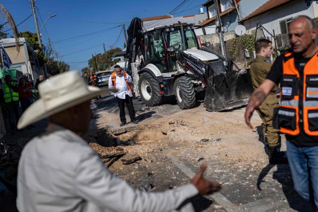 Security forces and residents gather next to a crater at the site of a strike in Rishon LeZion, on the outskirts of Tel Aviv, on March 17, 2026. On February 28, 2026, Israel and the United States launched strikes on Iran, killing its supreme leader and triggering a war that spread across the Middle East. (Photo by Ilia YEFIMOVICH / AFP) / 