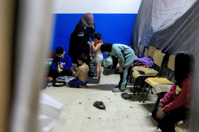 Members of a displaced family from southern Lebanon wait in a classroom at a school turned into a shelter in the southern coastal city of Sidon on March 17, 2026. After being forced to flee from Israeli air raids on southern Lebanon, families search in vain for alternative accommodations amid strict measures imposed by hotels and landlords afraid that guests might be targeted by Israel. In two weeks of war, Israel has carried out surprise strikes on two hotels, as well as on buildings in densely populated residential neighbourhoods. (Photo by Mahmoud ZAYYAT / AFP)