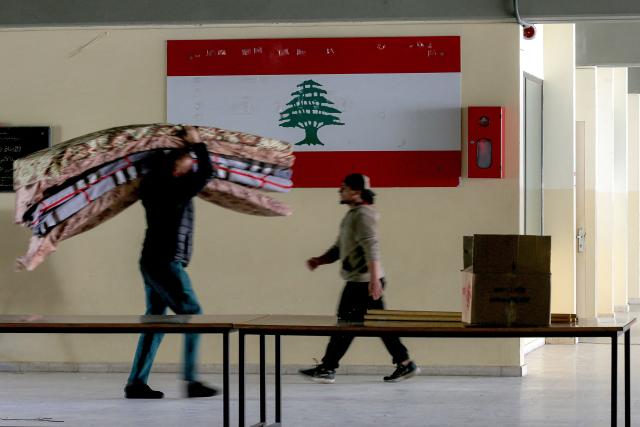 A volunteer carries mattresses for displaced people from southern Lebanon sheltering at a school in the southern coastal city of Sidon on March 17, 2026. After being forced to flee from Israeli air raids on southern Lebanon, families search in vain for alternative accommodations amid strict measures imposed by hotels and landlords afraid that guests might be targeted by Israel. In two weeks of war, Israel has carried out surprise strikes on two hotels, as well as on buildings in densely populated residential neighbourhoods. (Photo by MAHMOUD ZAYYAT / AFP)