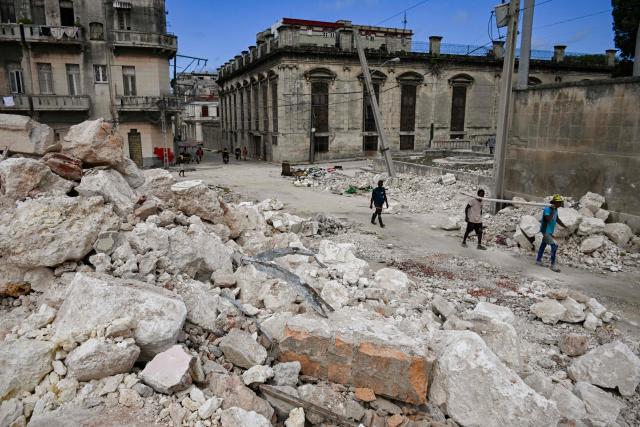 People walk next to the rubble of the National School of Design in Havana on March 16, 2026. Cuba scrambled on March 17, 2026, to restore power after a nationwide blackout that hit the communist-run island just as US President Donald Trump proclaimed he will "take" it over. (Photo by YAMIL LAGE / AFP)