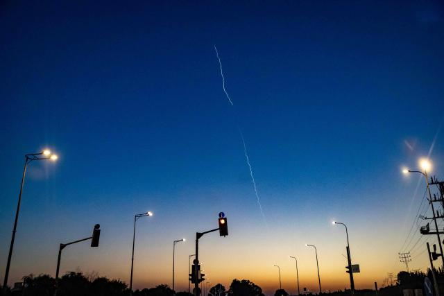 A rocket trail from Israel's Iron Dome missile defence system is seen in the sky from a car waiting at a red light near Afula, northern Israel on March 17, 2026. On February 28, 2026, Israel and the United States launched strikes on Iran, killing its supreme leader and triggering a war that spread across the Middle East. (Photo by Odd ANDERSEN / AFP) / 