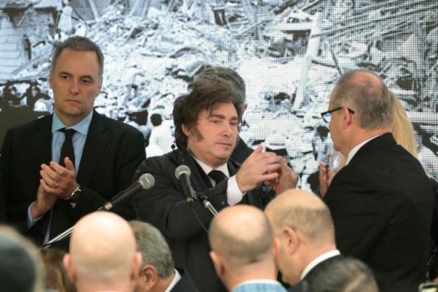 Argentina’s President Javier Milei (C) greets Israel ambassador to Argentina Eyal Sela (R) as next to his Chief of Cabinet Manuel Adorni (L) applauds, during a ceremony to commemorate the 34th anniversary of the bombing at the Israeli embassy in Buenos Aires that killed 29 people and wounded 200, at the Israeli Embassy Square in Buenos Aires on March 17, 2026. (Photo by JUAN MABROMATA / AFP)