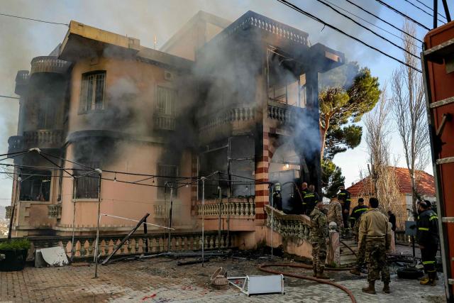Lebanese army soldiers and civil defence members inspect a building that burned following Israeli bombardment on the village of Marjayoun in southern Lebanon close to the border with Israel on March 17, 2026. Lebanon was drawn into the Middle East war on March 2 when pro-Iran Hezbollah launched rockets towards Israel in response to US-Israeli strikes that killed Iranian supreme leader Ayatollah Ali Khamenei. (Photo by AFP) / 
