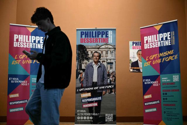 A supporter of Philippe Dessertine, independent candidate in the 2026 Bordeaux municipal election, looks at his mobile phone on stage  before he announces his withdrawal from the second round of voting during a press conference at the Maison Cantonale de la Bastide in Bordeaux, south-western France, on March 17, 2026 (Photo by Philippe LOPEZ / AFP)