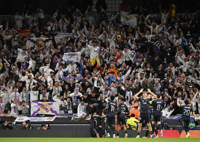 Real Madrid's Brazilian forward #07 Vinicius Junior is mobbed by teammates after scoring the opening goal from the penalty spot during the UEFA Champions League, round of 16 second leg football match between Manchester City and Real Madrid at the Etihad Stadium in Manchester, north west England, on March 17, 2026. (Photo by Oli SCARFF / AFP)