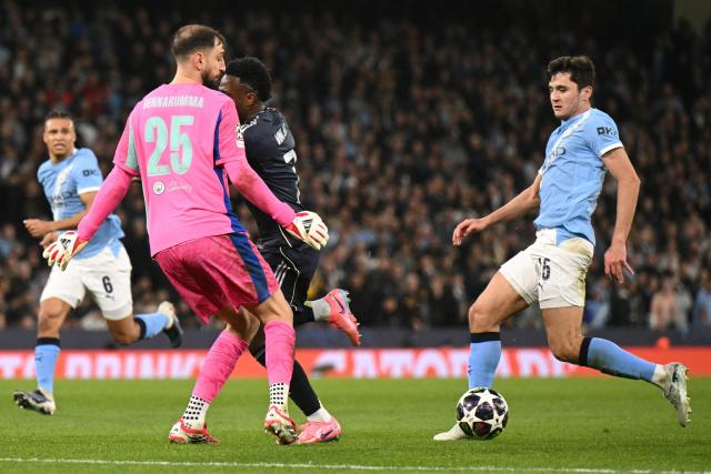 Real Madrid's Brazilian forward #07 Vinicius Junior (C) collides with Manchester City's Italian goalkeeper #25 Gianluigi Donnarumma (L) as he runs in on goal during the UEFA Champions League, round of 16 second leg football match between Manchester City and Real Madrid at the Etihad Stadium in Manchester, north west England, on March 17, 2026. (Photo by Oli SCARFF / AFP)