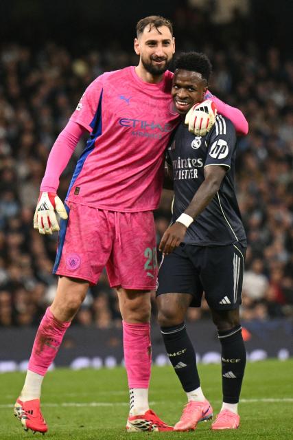 Real Madrid's Brazilian forward #07 Vinicius Junior (R) and Manchester City's Italian goalkeeper #25 Gianluigi Donnarumma (L) embrace during the UEFA Champions League, round of 16 second leg football match between Manchester City and Real Madrid at the Etihad Stadium in Manchester, north west England, on March 17, 2026. (Photo by Oli SCARFF / AFP)