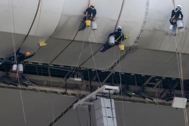 Workers clean the roof of Akron Stadium, home of the Guadalajara soccer club, in Zapopan, Jalisco, Mexico on March 17, 2026. Akron Stadium will host two World Cup playoff matches next week and will be one of Mexico’s three venues for the 2026 World Cup. (Photo by ULISES RUIZ / AFP)