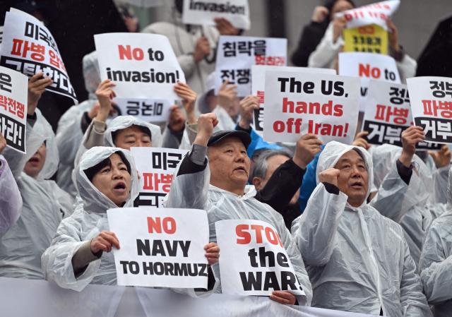 South Korean protesters hold placards during a rally condemning the US and Israeli attacks on Iran, near the US embassy in Seoul on March 18, 2026. (Photo by Jung Yeon-je / AFP)