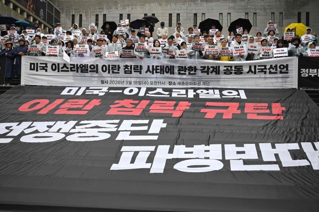 South Korean protesters hold placards as a big black banner reads "Stop the war, oppose troops deployment" during a rally condemning the US and Israeli attacks on Iran, near the US embassy in Seoul on March 18, 2026. (Photo by Jung Yeon-je / AFP)