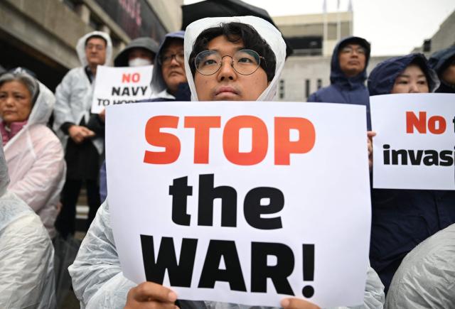 South Korean protesters hold placards during a rally condemning the US and Israeli attacks on Iran, near the US embassy in Seoul on March 18, 2026. (Photo by Jung Yeon-je / AFP)
