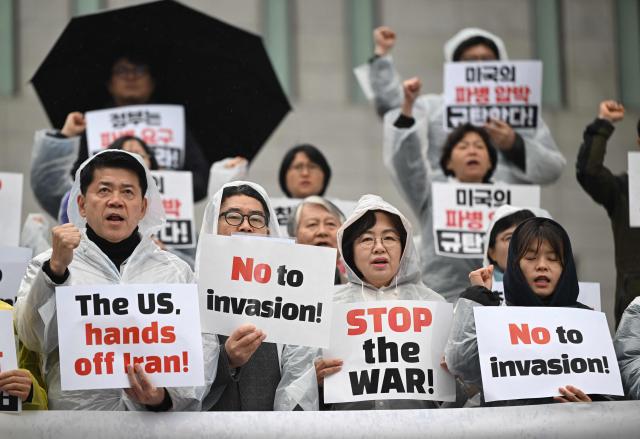 South Korean protesters hold placards during a rally condemning the US and Israeli attacks on Iran, near the US embassy in Seoul on March 18, 2026. (Photo by Jung Yeon-je / AFP)