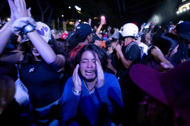 A Venezuelan fan reacts as she celebrates her national baseball team's victory in the final of the 2026 World Baseball Classic against the United States team, in Caracas on March 17, 2026. Venezuela, where baseball is the national sport, capped off its dream tournament by defeating the favorite, the United States, on home soil, amid tense relations between the two governments following the capture of President Nicolás Maduro by U.S. forces in January. (Photo by Juan BARRETO / AFP)