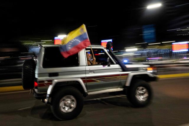 A Venezuelan fan waves a national flag as she celebrates her national baseball team's victory in the final of the 2026 World Baseball Classic against the United States team, in Caracas on March 17, 2026. Venezuela, where baseball is the national sport, capped off its dream tournament by defeating the favorite, the United States, on home soil, amid tense relations between the two governments following the capture of President Nicolás Maduro by U.S. forces in January. (Photo by Juan BARRETO / AFP)