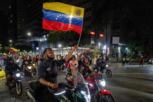 A Venezuelan fan waves a national flag as he celebrates his national baseball team's victory in the final of the 2026 World Baseball Classic against the United States team, in Caracas on March 17, 2026. Venezuela, where baseball is the national sport, capped off its dream tournament by defeating the favorite, the United States, on home soil, amid tense relations between the two governments following the capture of President Nicolás Maduro by U.S. forces in January. (Photo by Juan BARRETO / AFP)