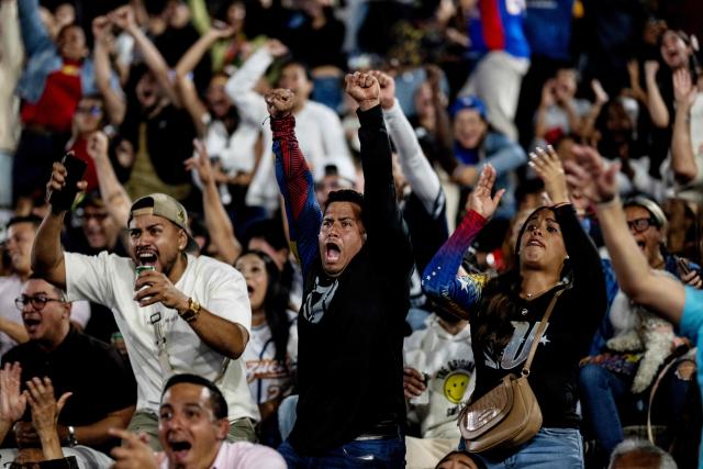Venezuelan fans celebrate their national baseball team's victory in the final of the 2026 World Baseball Classic against the United States team, in Caracas on March 17, 2026. Venezuela, where baseball is the national sport, capped off its dream tournament by defeating the favorite, the United States, on home soil, amid tense relations between the two governments following the capture of President Nicolás Maduro by U.S. forces in January. (Photo by Juan BARRETO / AFP)