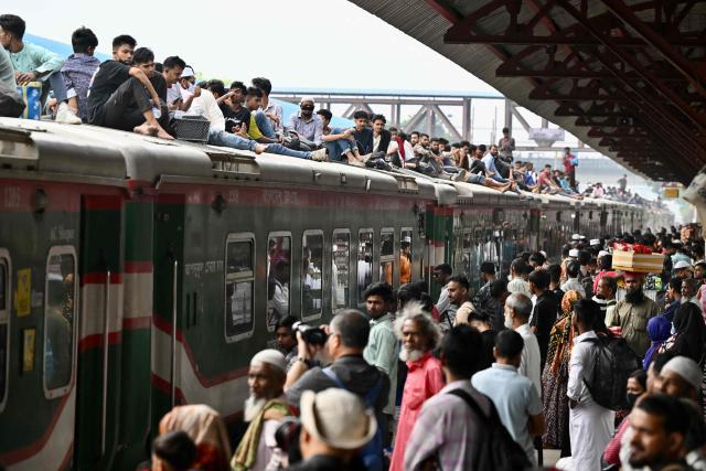 Bangladeshis sit atop a train at a railway station in Tongi on March 18, 2026 as they return to their hometowns ahead of the Muslim festival of Eid al-Fitr. (Photo by MUNIR UZ ZAMAN / AFP)