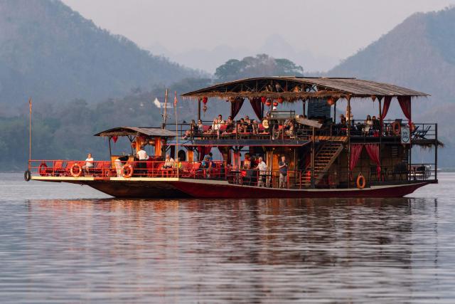 A sunset cruise boat glides along along the Mekong river in Luang Prabang on March 16, 2026. (Photo by AFP)
