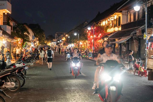 Motorists drive on a street through a night market in Luang Prabang on March 16, 2026. (Photo by AFP)
