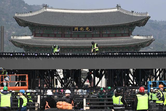 This picture taken on March 16, 2026 shows workers setting up the stage for a comeback concert of K-pop boy group BTS in front of Gwanghwamun Gate (top), the main gate of Gyeongbokgung Palace, in Seoul. More than a quarter of a million fans are expected to throng central Seoul on March 21 for BTS's open-air gig, the first performance in almost four years by the boy band seen as the biggest in the world. (Photo by Jung Yeon-je / AFP)