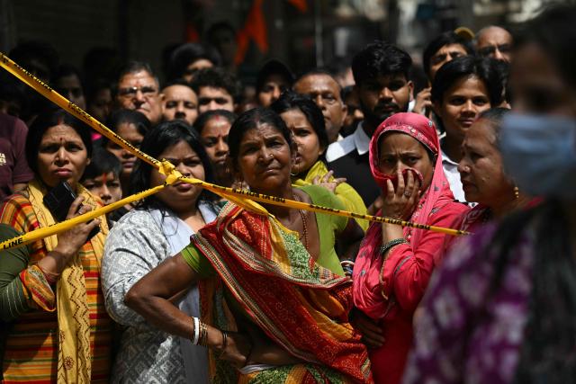 Onlookers gather after a fire broke out at a residential building in New Delhi on March 18, 2026. (Photo by Arun SANKAR / AFP)