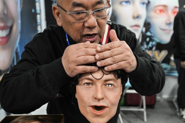 A man talks to a robot that mimics human expressions from Shenzhen Xiaoquan Technology during the International AI Application and Robotics Innovation Exhibition in Beijing on March 18, 2026. (Photo by ADEK BERRY / AFP)