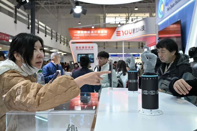 People check bionic hands from Yuequan Bionics during the International AI Application and Robotics Innovation Exhibition in Beijing on March 18, 2026. (Photo by ADEK BERRY / AFP)