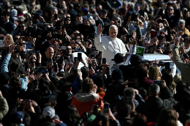Pope Leo XIV waves to the crowd during the weekly general audience at St Peter's Square in The Vatican on March 18, 2026. (Photo by Andreas SOLARO / AFP)