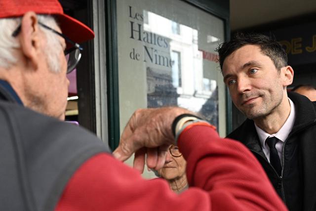 French far-right party Rassemblement National (RN) candidate for mayor of Nimes Julien Sanchez (R) speaks with a local resident as he campaigns in Nimes, southern France on March 18, 2026, ahead of the second round of the municipal elections. (Photo by Gabriel BOUYS / AFP)