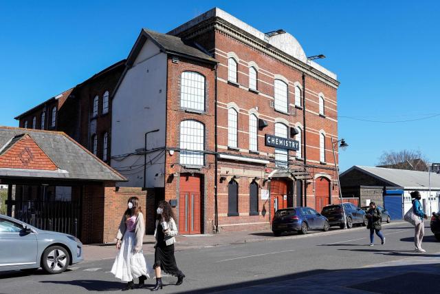 Pedestrians wearing face masks walk past Club Chemistry (C), a nightclub linked to a recent outbreak of meningitis in Canterbury, south-east England on March 18, 2026. The number of meningitis cases being probed by UK authorities has risen to 20, health officials said on March 18, following an "unprecedented" deadly outbreak centred on a university. The outbreak in Kent in southeastern England has claimed the lives of two young people -- a 21-year-old university student and an 18-year-old school student. (Photo by CARLOS JASSO / AFP)