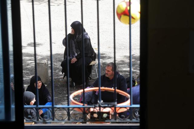 Displaced families from southern Lebanon, sit at the courtyard of a school turned into a shelter in the southern coastal city of Sidon on March 18, 2026. Lebanon was drawn into the Middle East war on March 2 when militant group Hezbollah launched rockets into Israel to avenge the killing of Iran's supreme leader Ayatollah Ali Khamenei. Israel responded with intense strikes on multiple regions around the country and by launching ground operations in the south. (Photo by MAHMOUD ZAYYAT / AFP)