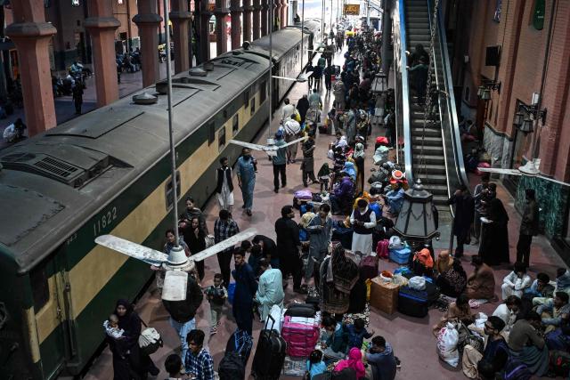 Passengers board a train at a railway station in Lahore on March 18, 2026, as they head to their hometowns for the upcoming Eid al-Fitr festivities, which mark the end of the Muslim holy fasting month of Ramadan. (Photo by Arif ALI / AFP)