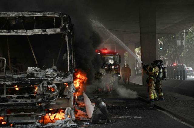 Firefighters work to put out a fire on a bus allegedly set by drug traffickers with home extinguishers during a police operation in central Rio de Janeiro, Brazil, on March 18, 2026. (Photo by Mauro PIMENTEL / AFP)