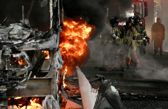 Firefighters work to put out a fire on a bus allegedly set by drug traffickers with home extinguishers during a police operation in central Rio de Janeiro, Brazil, on March 18, 2026. (Photo by Mauro PIMENTEL / AFP)
