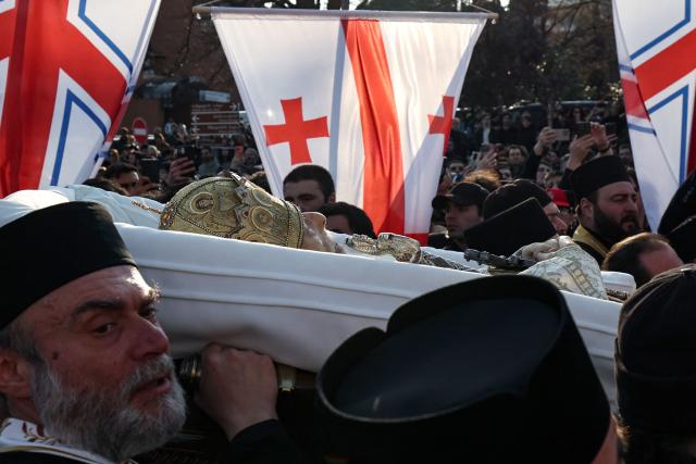 Clergymen carry the coffin with the body of the late Georgia's Orthodox Patriarch Ilia II prior to a memorial service to be held at the Sameba Cathedral in Tbilisi on March 18, 2026. Georgian Orthodox Church leader Ilia II died on March 17, 2026 aged 93, the church said, after nearly half a century at the helm of one of the country's most powerful institutions. (Photo by Giorgi ARJEVANIDZE / AFP)
