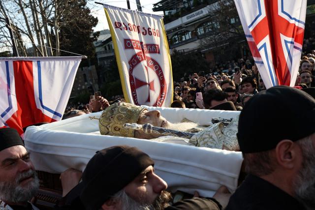 Clergymen carry the coffin with the body of the late Georgia's Orthodox Patriarch Ilia II prior to a memorial service to be held at the Sameba Cathedral in Tbilisi on March 18, 2026. Georgian Orthodox Church leader Ilia II died on March 17, 2026 aged 93, the church said, after nearly half a century at the helm of one of the country's most powerful institutions. (Photo by Giorgi ARJEVANIDZE / AFP)