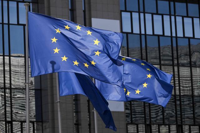 This photograph shows European flags fluttering outside the EU Council headquarters in Brussels on March 18, 2026. (Photo by Nicolas TUCAT / AFP)