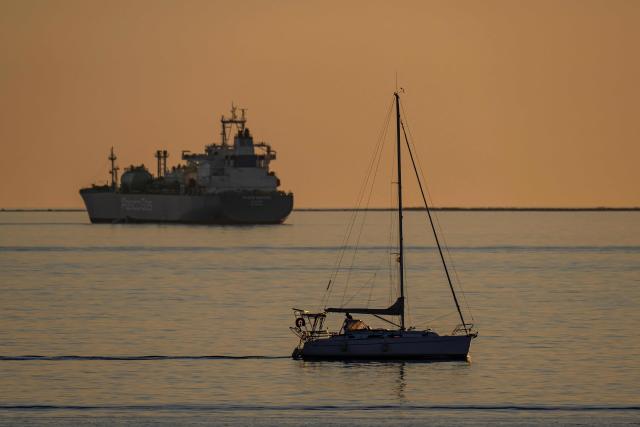 This photograph taken from Port de Bouc shows a sailboat sailing next the to Oil and Chemical Tanker PascoGas anchored in the Grand Port Maritime de Marseille-Fos in Fos-sur-Mer, off the Mediterranean coast of southern France on March 17, 2026. (Photo by MIGUEL MEDINA / AFP)