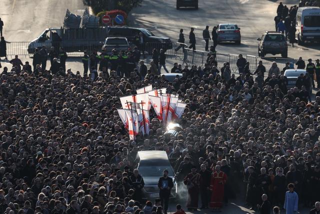 Mourners follow the hearse transporting the coffin with the body of the late Georgia's Orthodox Patriarch Ilia II prior to a memorial service to be held at the Sameba Cathedral in Tbilisi on March 18, 2026. Georgian Orthodox Church leader Ilia II died on March 17, 2026 aged 93, the church said, after nearly half a century at the helm of one of the country's most powerful institutions. (Photo by Giorgi ARJEVANIDZE / AFP)