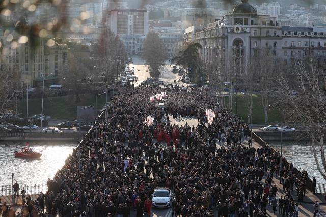 Mourners follow the hearse transporting the coffin with the body of the late Georgia's Orthodox Patriarch Ilia II prior to a memorial service to be held at the Sameba Cathedral in Tbilisi on March 18, 2026. Georgian Orthodox Church leader Ilia II died on March 17, 2026 aged 93, the church said, after nearly half a century at the helm of one of the country's most powerful institutions. (Photo by Giorgi ARJEVANIDZE / AFP)